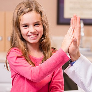 Young girl laughing and giving dentist a high five