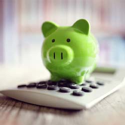 Piggy bank atop calculator representing insurance coverage for children’s dental emergencies in Casper