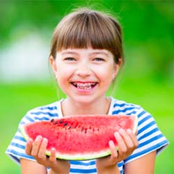 Smiling girl with watermelon after visiting Casper pediatric dentist