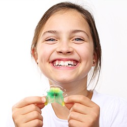 Smiling girl holding oral appliance