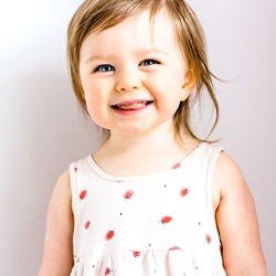 A little girl wearing a dress and smiling after seeing her pediatric dentist in Casper