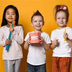 Three happy kids with healthy smiles after dental sealants
