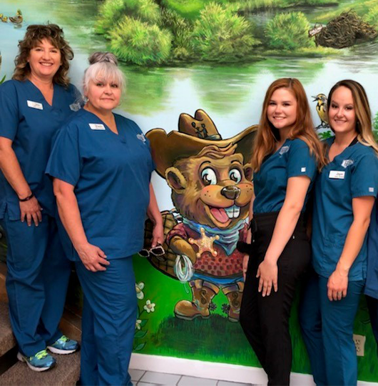 Casper pediatric dental tech team next to mural of cartoon beaver