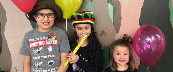 Three kids wearing fun hats and holding props in Casper pediatric dental office