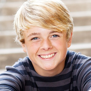 Smiling young boy sitting on steps outdoors