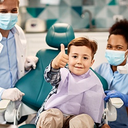 Happy little boy in dental treatment chair, making thumbs up gesture
