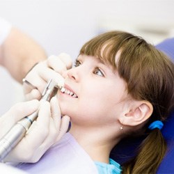 A closeup of a dentist cleaning a child’s teeth