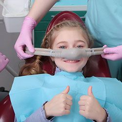 young girl giving thumbs up under dental sedation