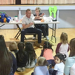 Dentist talking to group of kids about flossing