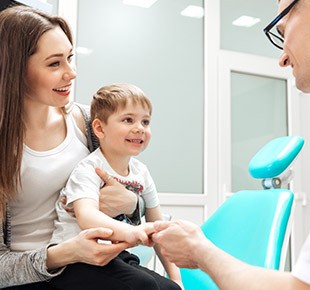 Mother holding young child in lap during dental appointment