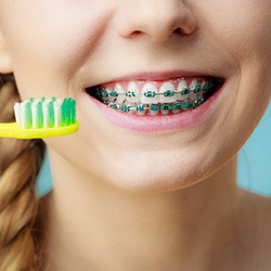 a child cleaning their traditional braces with a toothbrush