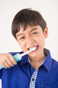 young boy using electric toothbrush 