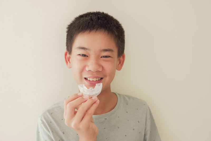Smiling boy holding mouthguard up to face