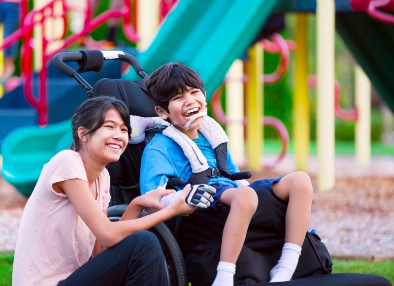 A mother and her special needs child smiling with good oral health at a playground