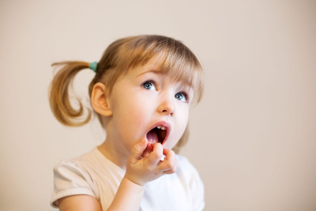 Girl with pigtails touching her bottom teeth