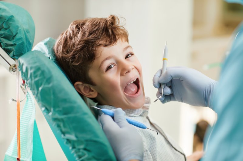 A young boy smiling while sitting in a dentist’s chair